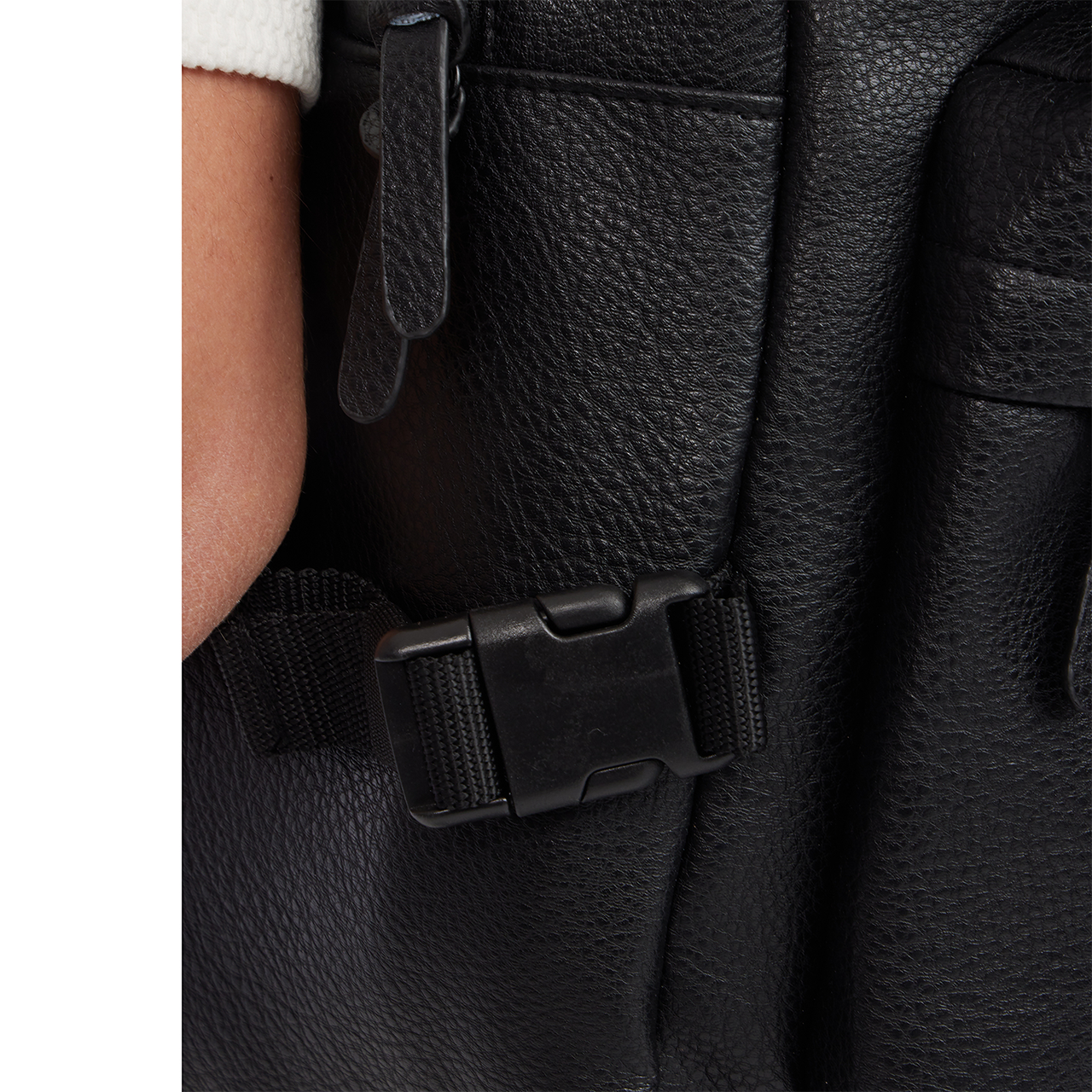 Close-up of a black leather backpack with a buckle detail.