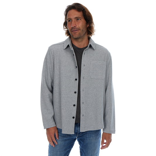 Man wearing a gray button-up shirt over a black shirt on a white background