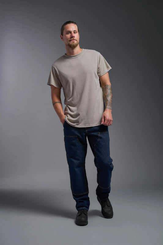 Man wearing a plain gray t-shirt and blue jeans against a gray background