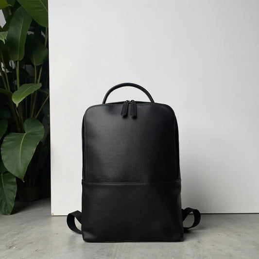 Black leather slim backpack with curved handle and adjustable shoulder straps