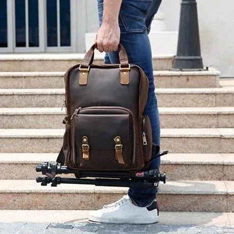 Camera backpack worn outdoors with adjustable straps and camera setup on a tripod base