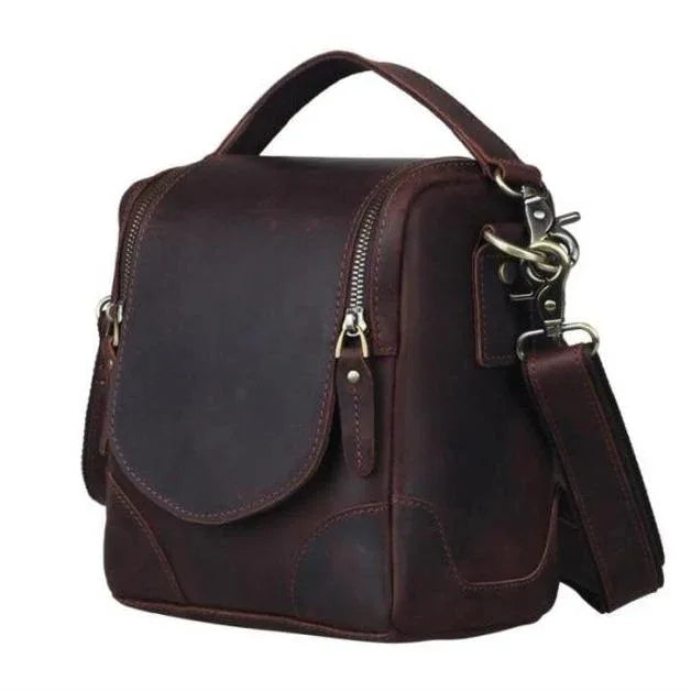 Brown leather camera bag with front flap, brass hardware, and crossbody strap