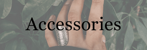 Women's accessories banner with a ring on a finger in front of foliage.