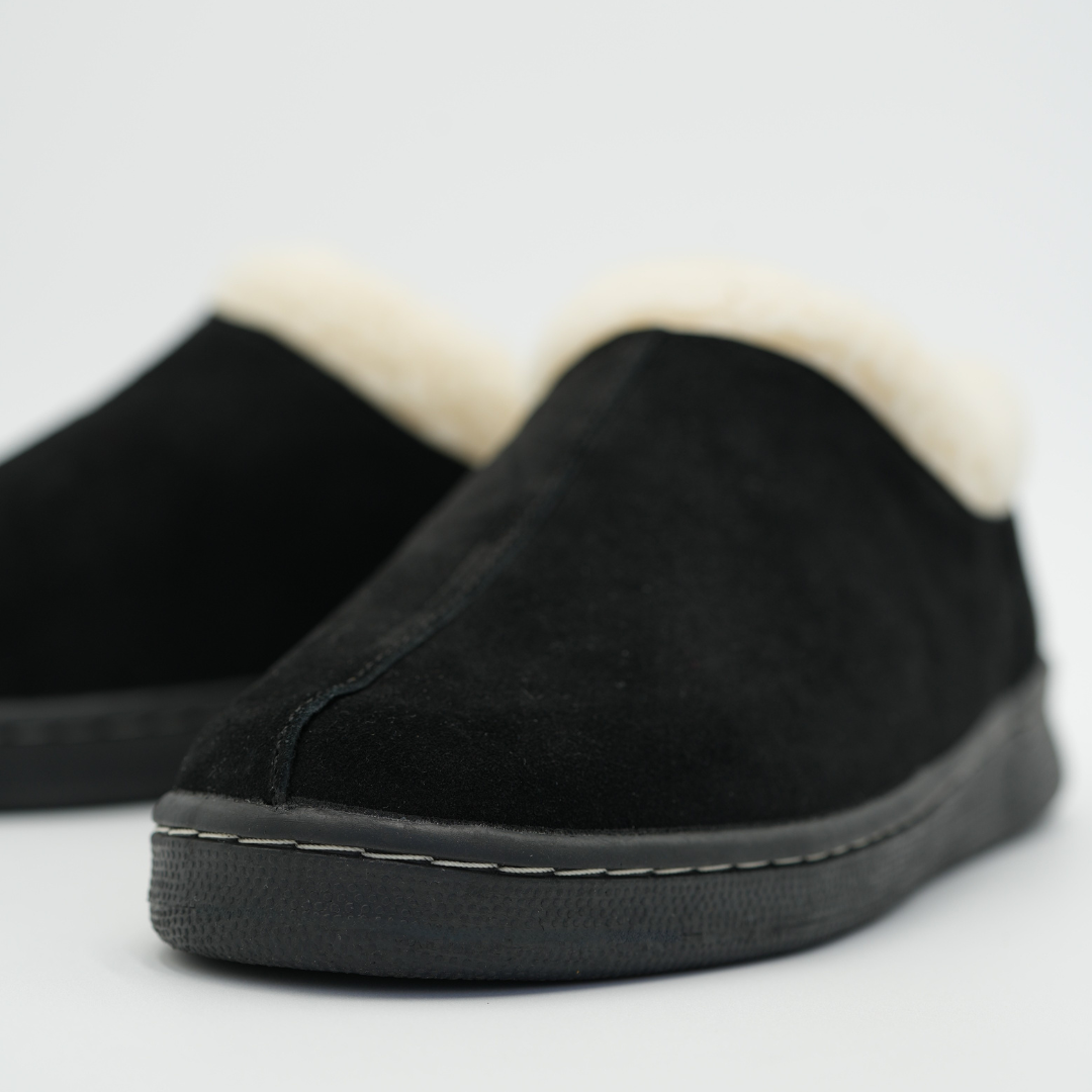 Black slip-on shoes with white lining on a light gray background
