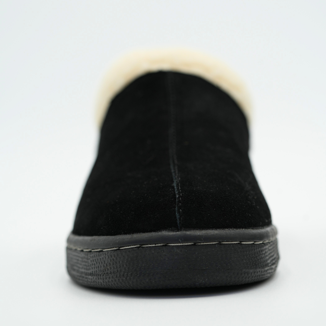 Black slip-on shoe with white fur lining on a light gray background