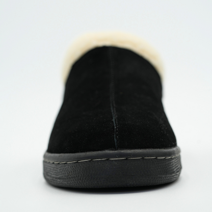 Black slip-on shoe with white fur lining on a light gray background