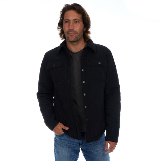 Man wearing a black jacket over a dark shirt with blue jeans on a white background