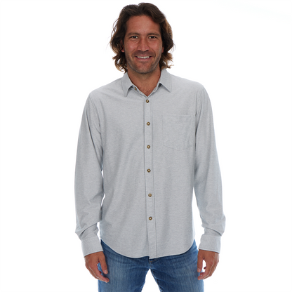 Man wearing a light gray button-up shirt and blue jeans on a white background