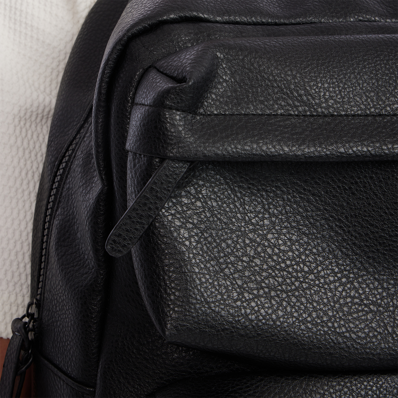 Close-up of a black leather bag with visible stitching
