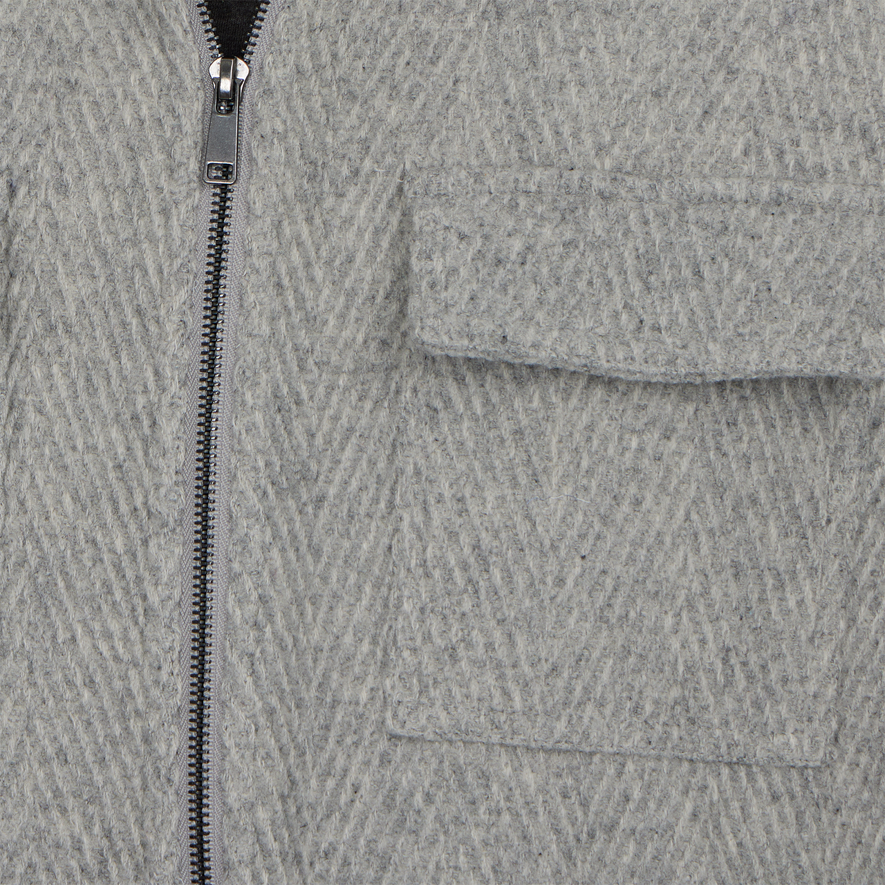 Close-up of a gray textured fabric with a zipper and pocket