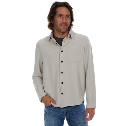 Man wearing a light gray button-up shirt and blue jeans on a white background