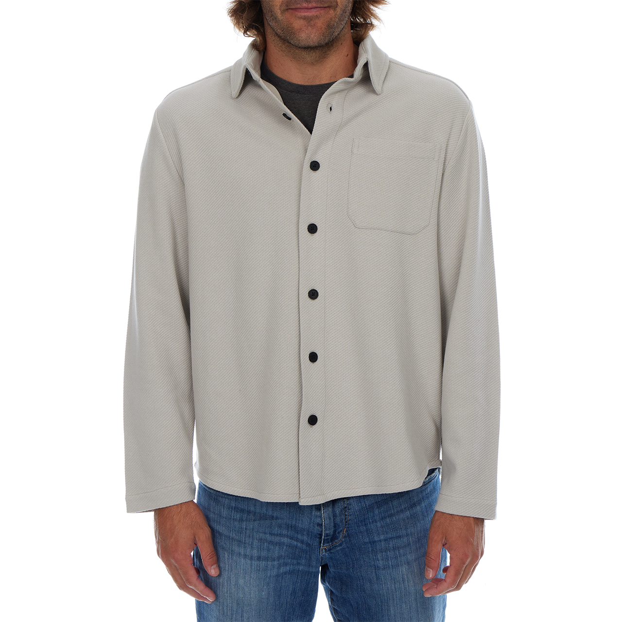 Man wearing a light gray button-up shirt with black buttons on a white background