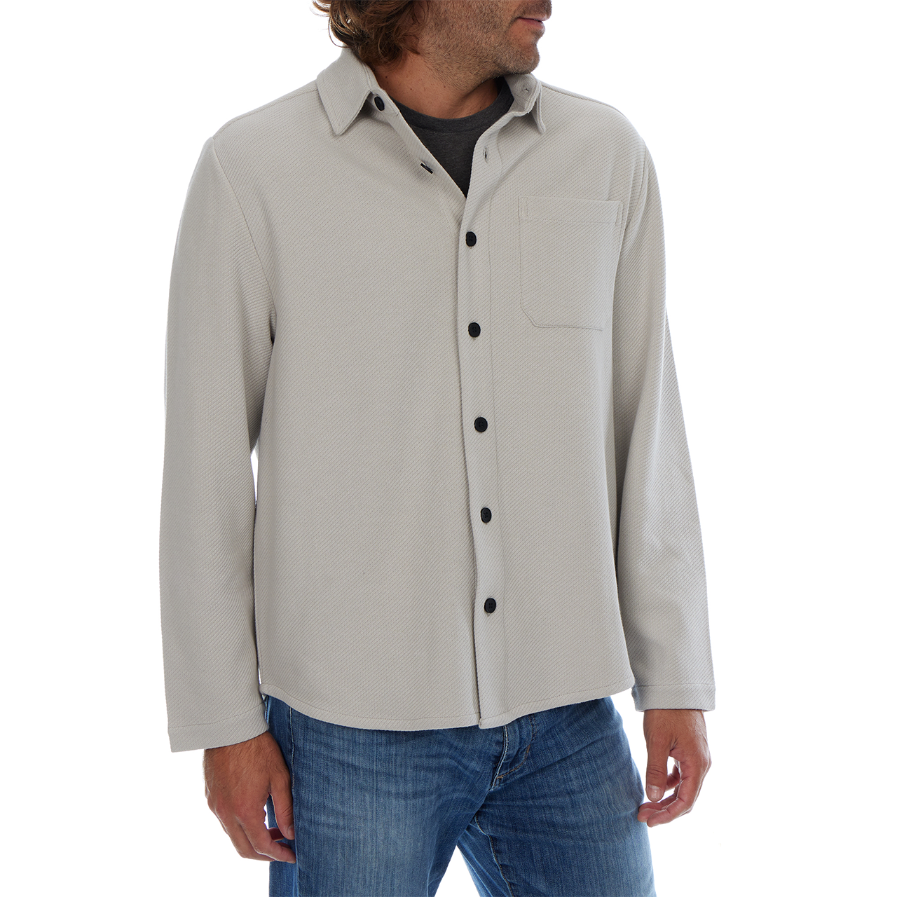 Man wearing a light gray button-up shirt with black buttons on a white background