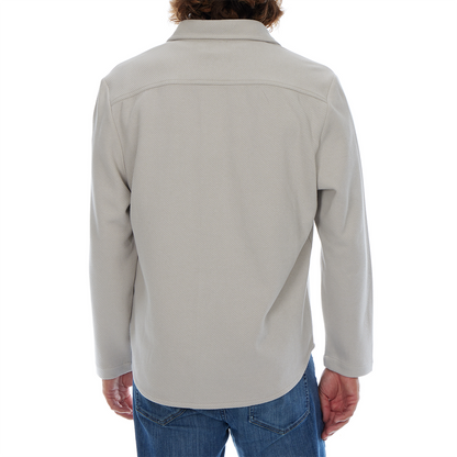 Person wearing a light gray jacket and blue jeans on a white background