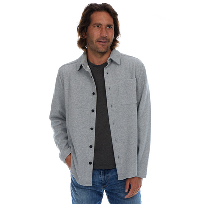 Man wearing a gray button-up shirt over a black t-shirt on a white background
