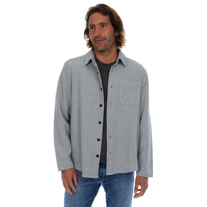 Man wearing a gray button-up shirt over a black shirt on a white background