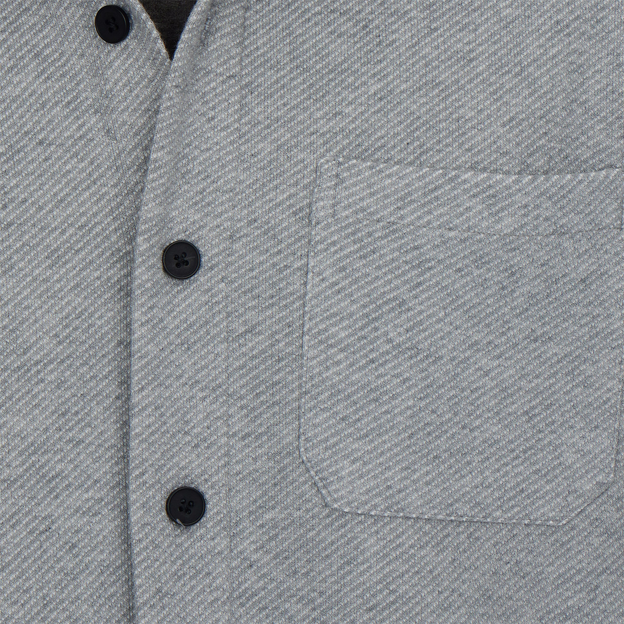 Close-up of a gray textured shirt with black buttons and a pocket.