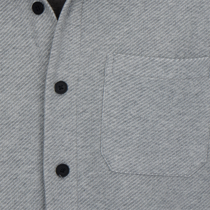 Close-up of a gray textured shirt with black buttons and a pocket.