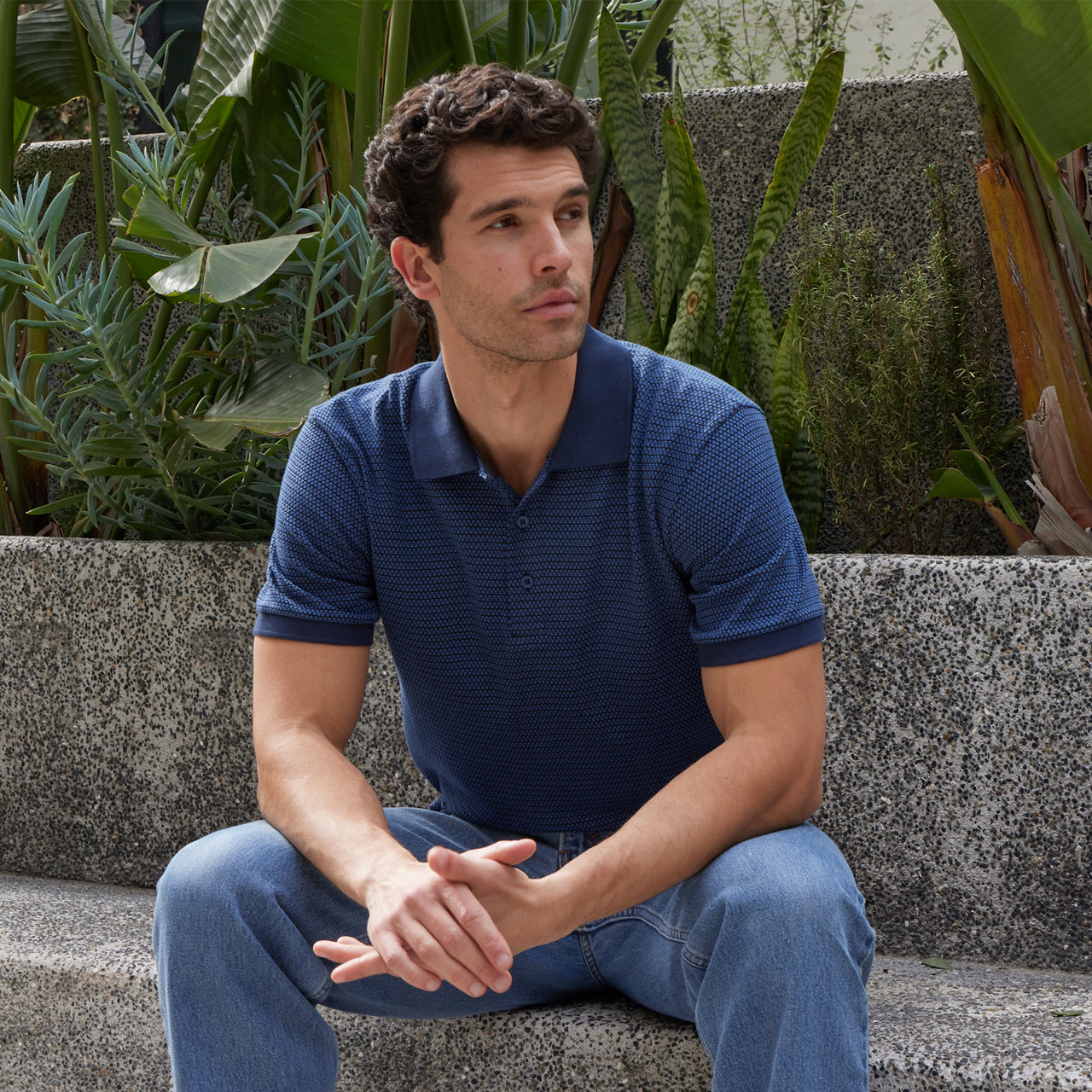 Man sitting outdoors with plants in the background