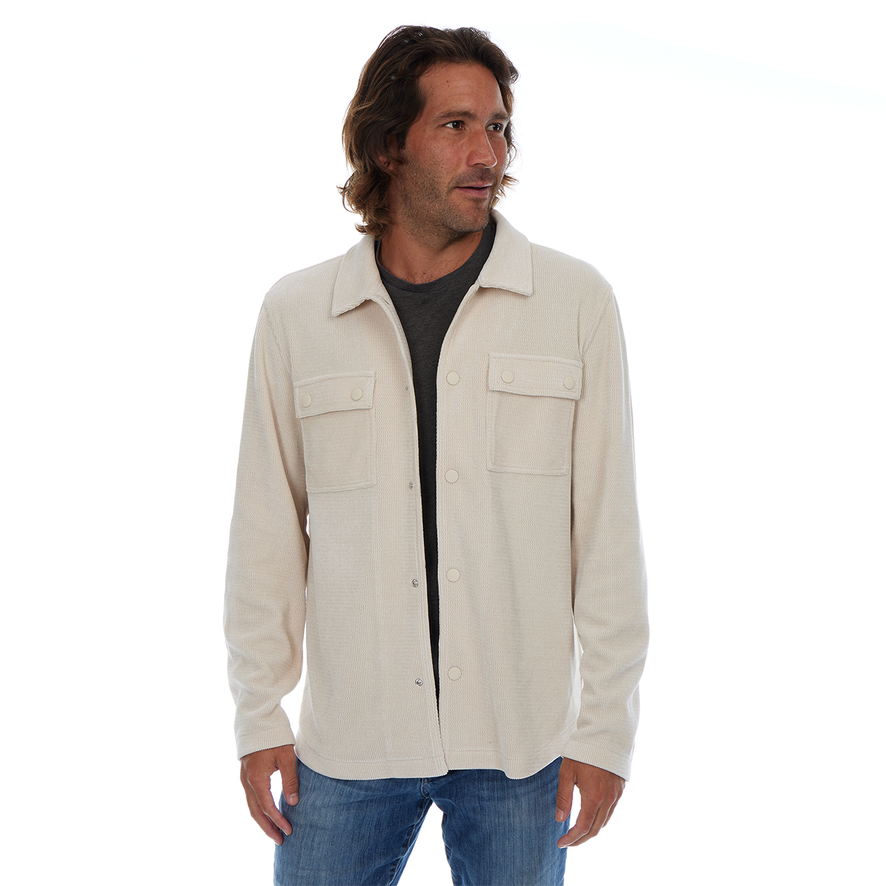 Man wearing a beige shirt over a black shirt on a white background