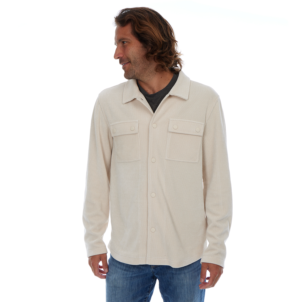 Man wearing a beige button-up shirt and blue jeans on a white background