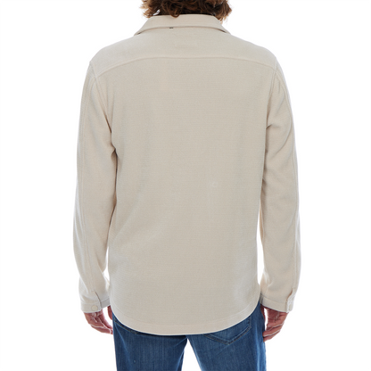 Person wearing a beige long-sleeve shirt on a white background