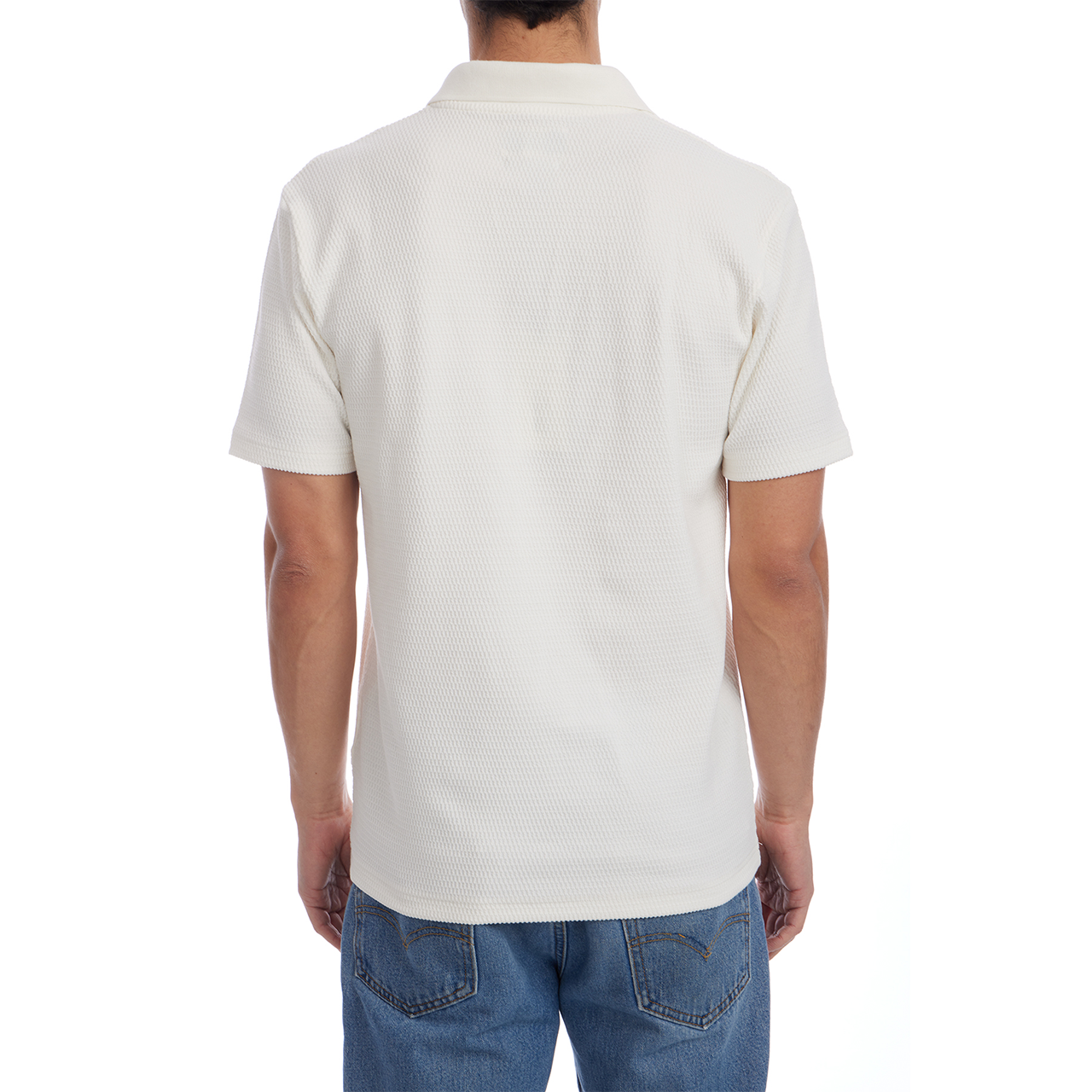 Person wearing a white textured polo shirt and blue jeans on a white background