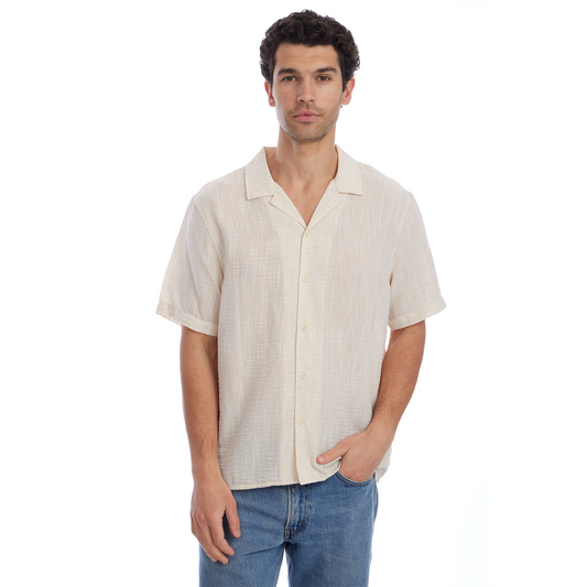 Man wearing a beige short-sleeve shirt and blue jeans on a white background
