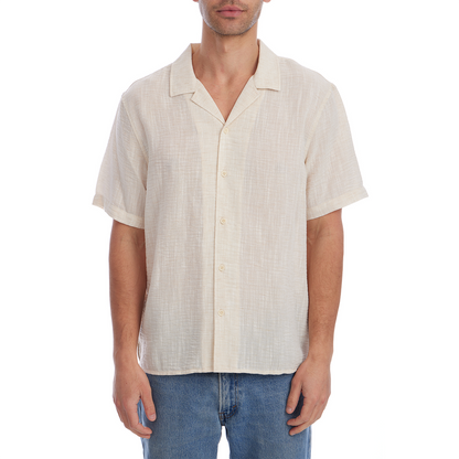 Man wearing a beige short-sleeve shirt and blue jeans on a white background