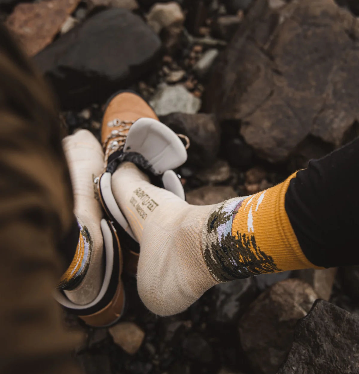 Close-up of hiking boots and socks with a rocky background