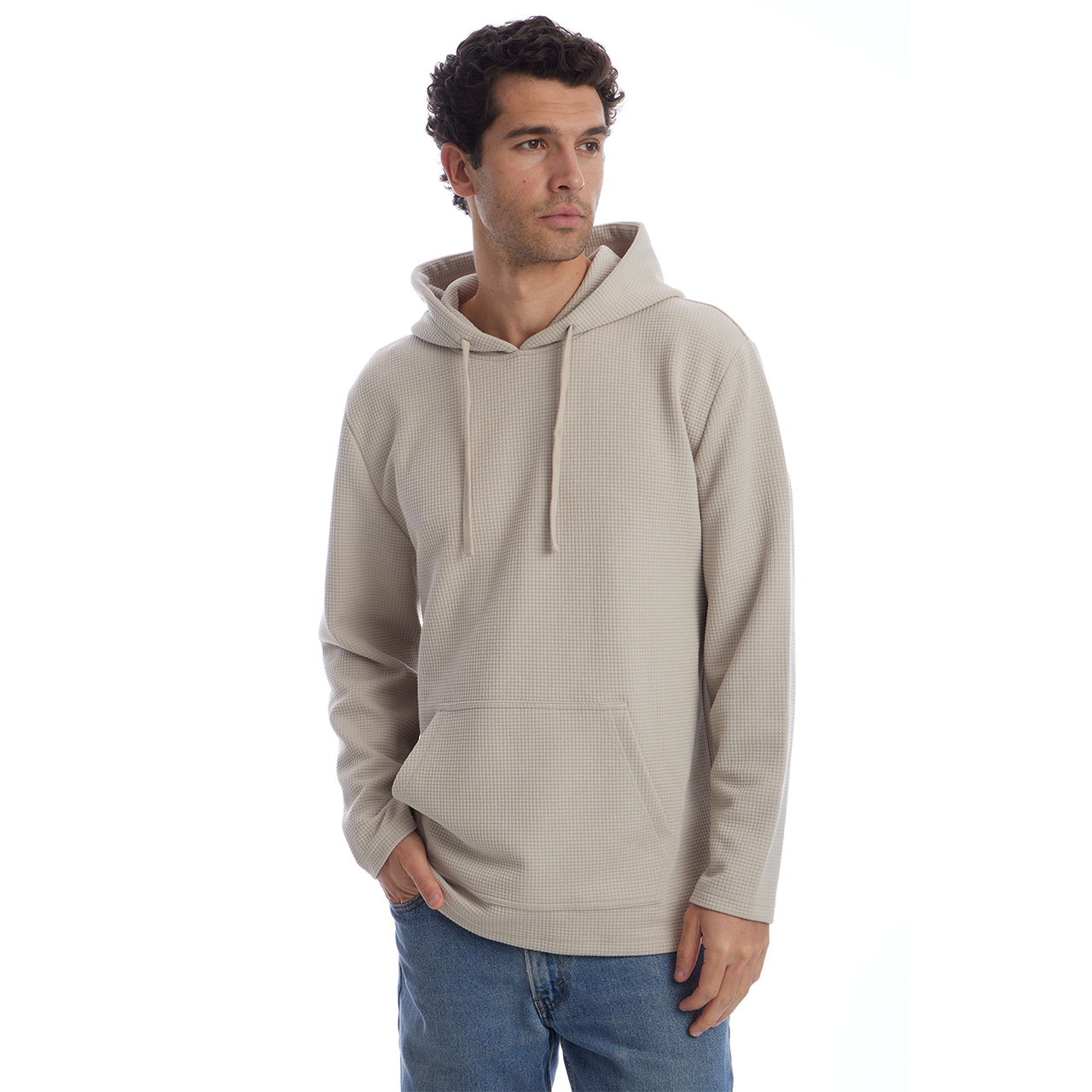 Man wearing a beige hoodie and blue jeans on a white background