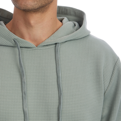 Close-up of a person wearing a textured green hoodie on a white background