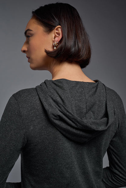 Woman wearing a dark gray hoodie against a gray background