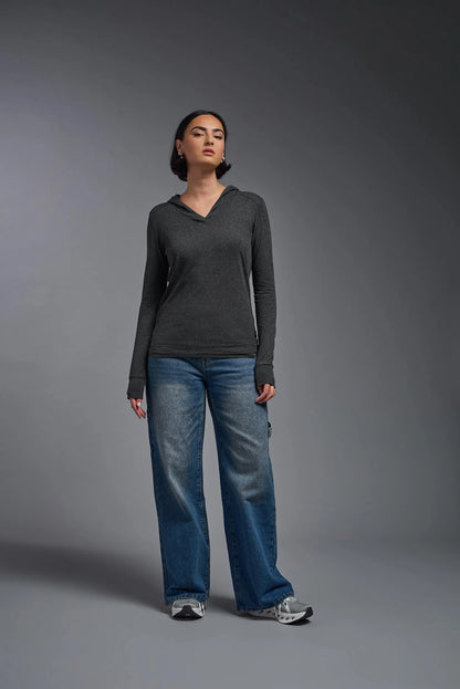 Person wearing a dark gray long-sleeve shirt and blue jeans against a gray background
