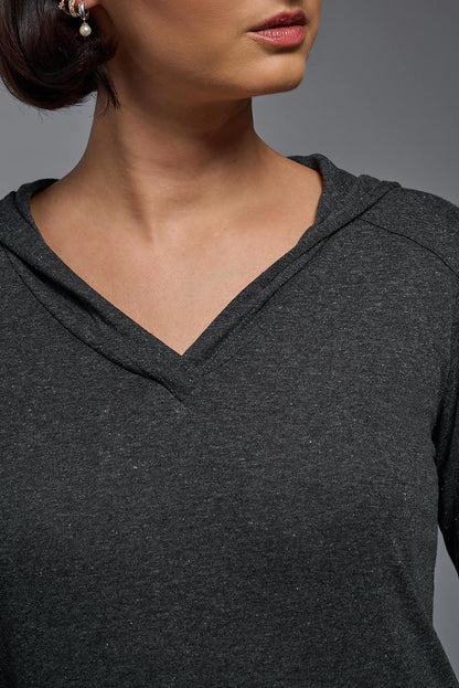 Close-up of a person wearing a dark gray hoodie against a gray background