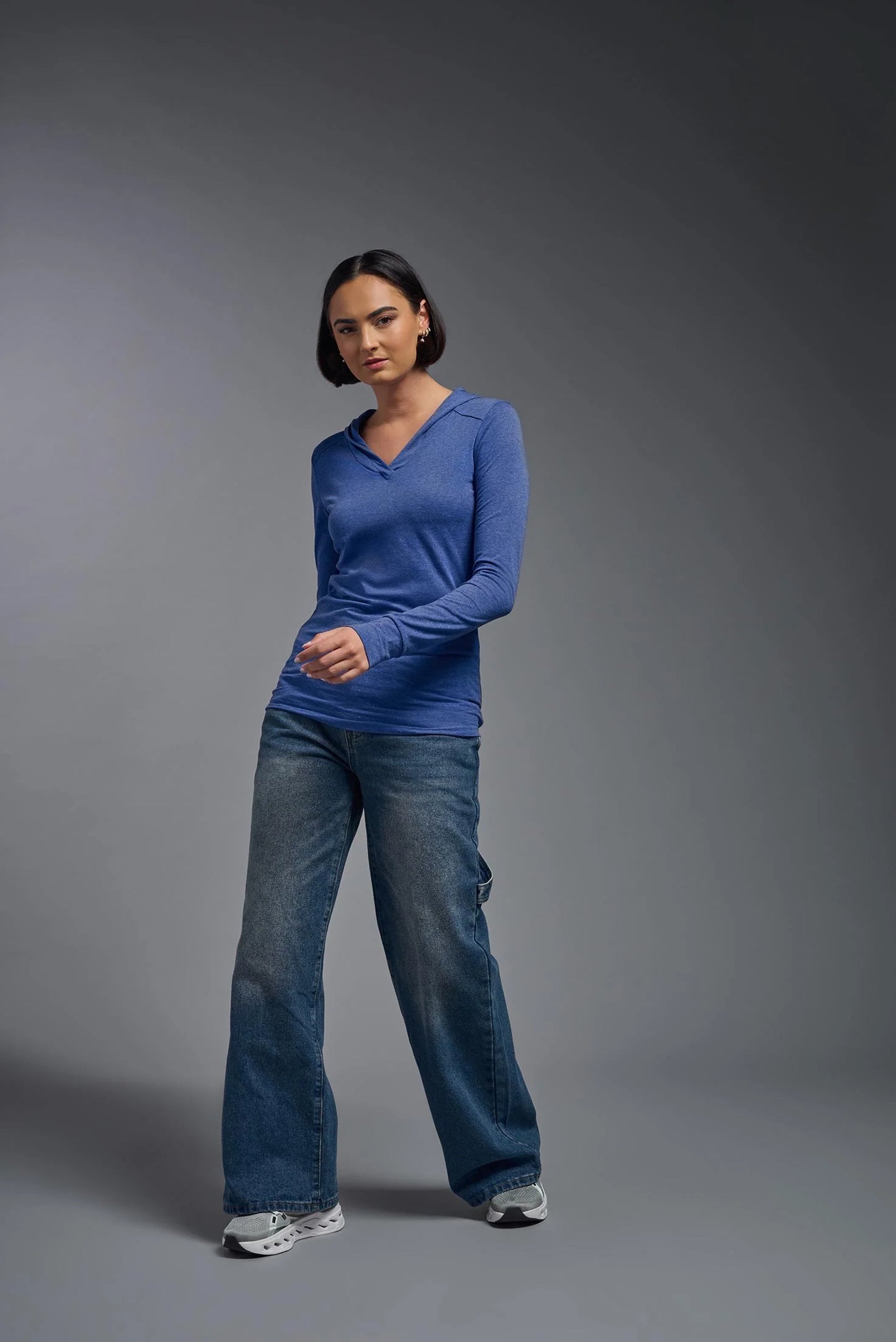 Person wearing a blue long-sleeve shirt and jeans on a gray background