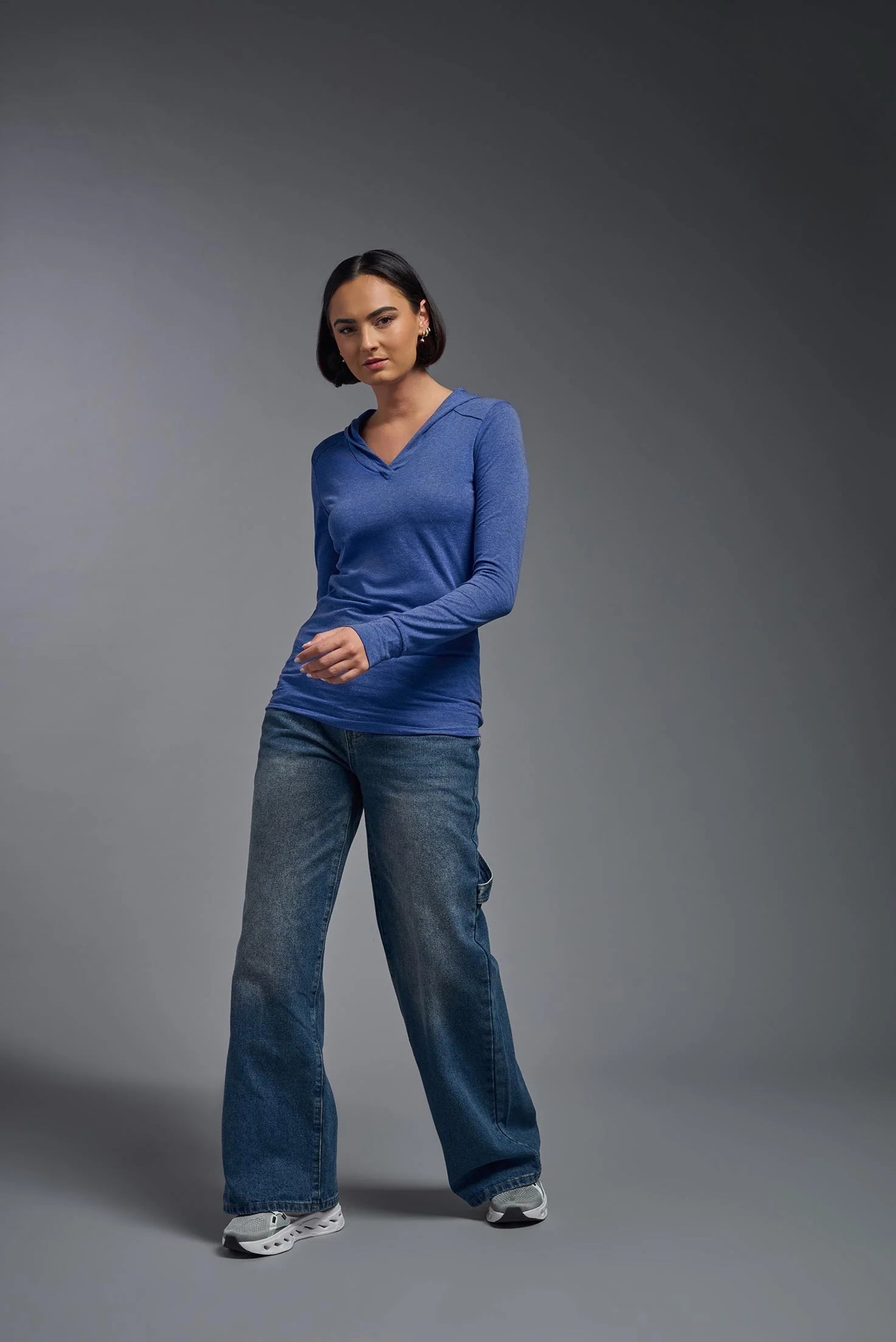 Person wearing a blue long-sleeve shirt and jeans on a gray background