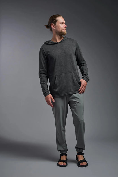 Man wearing a dark gray hoodie and pants on a gray background