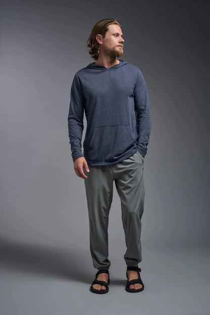 Man wearing a blue hoodie and gray pants against a gray background