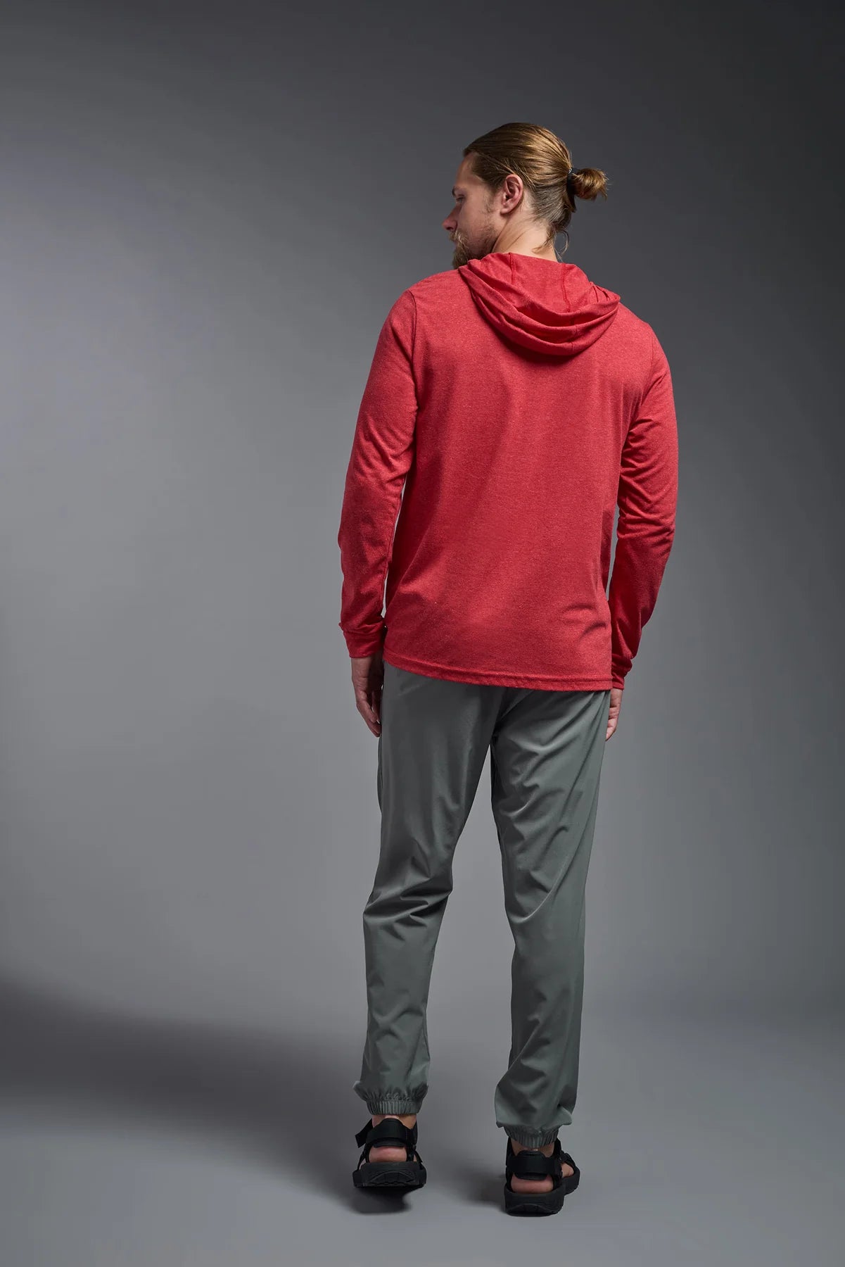 Person wearing a red hoodie and gray pants against a gray background