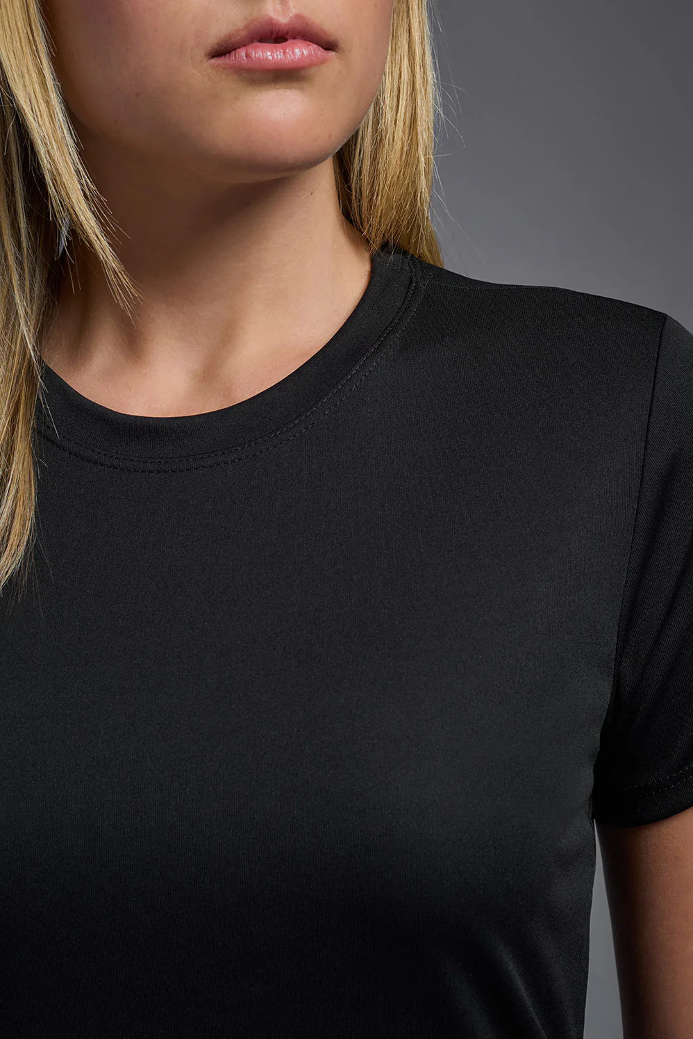 Person wearing a plain black t-shirt against a gray background