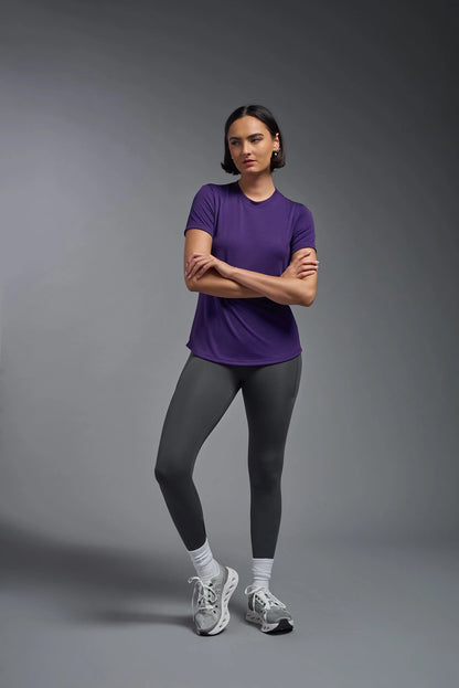 Person wearing a purple shirt and gray leggings on a gray background
