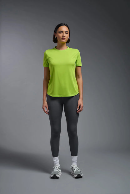 Person wearing a bright green t-shirt and gray leggings on a gray background