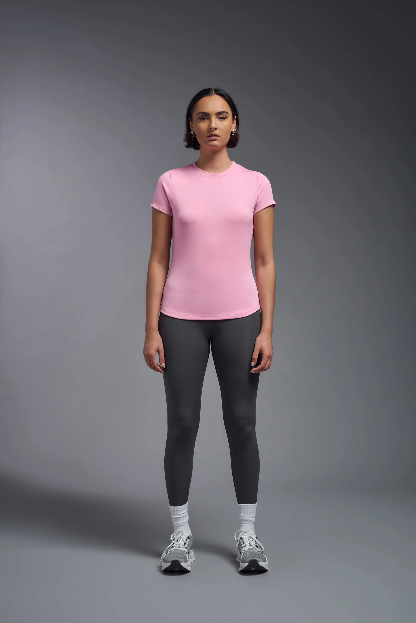 Person wearing a pink t-shirt and gray leggings on a gray background