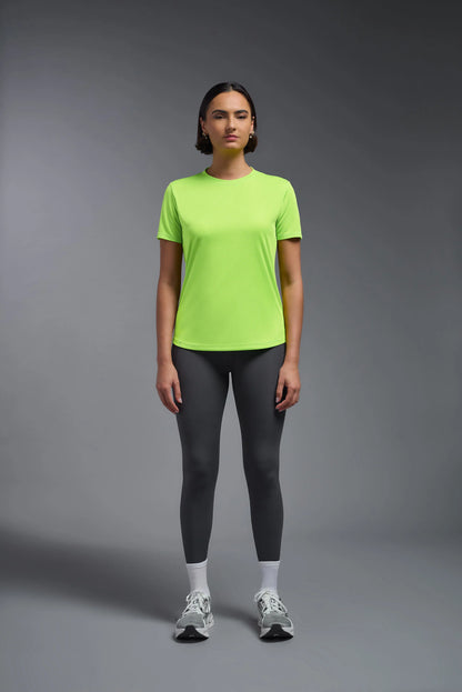 Person wearing a bright green t-shirt and gray leggings on a gray background
