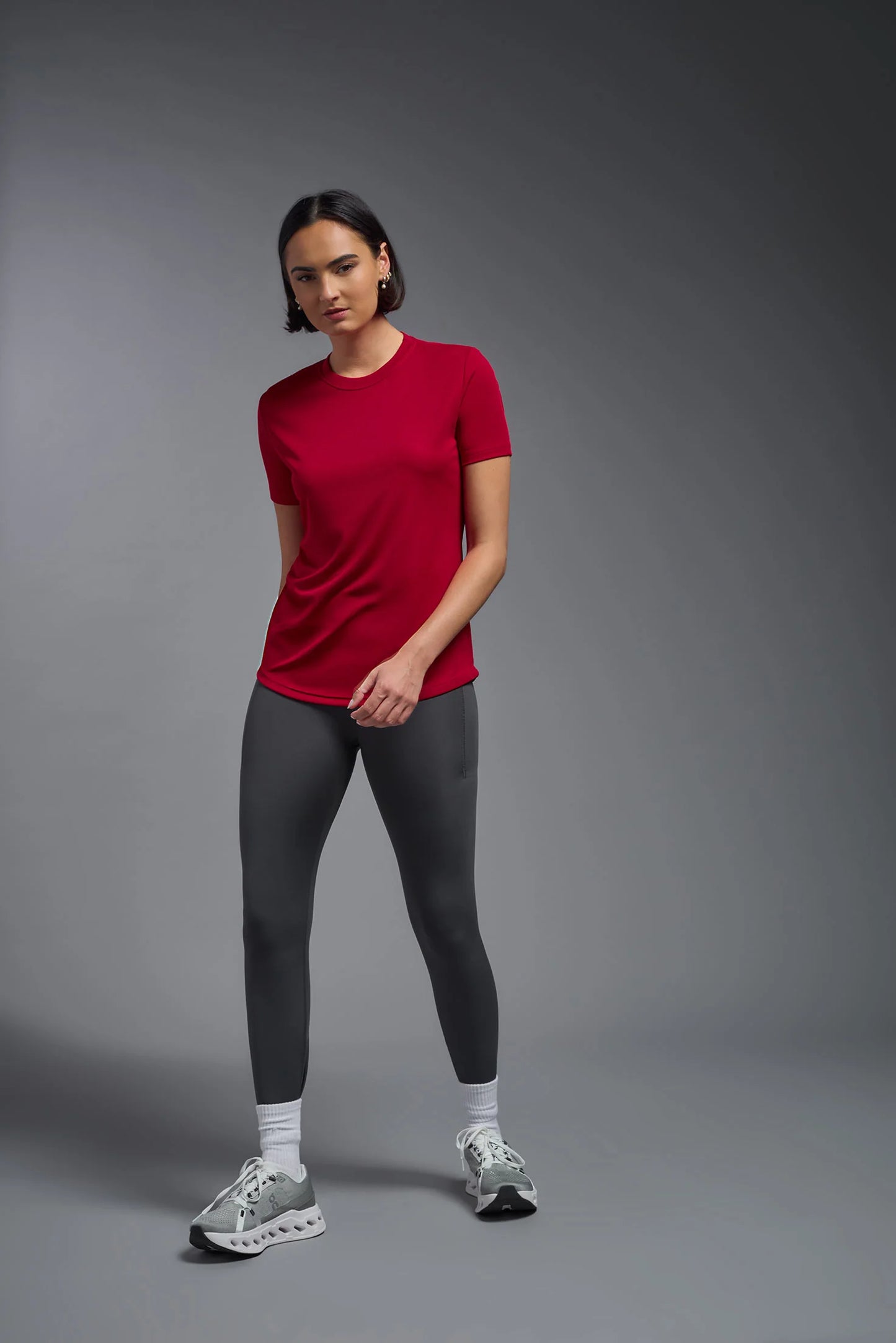 Person wearing a red t-shirt and black leggings on a gray background