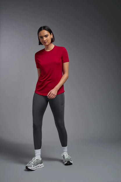 Person wearing a red t-shirt and black leggings on a gray background