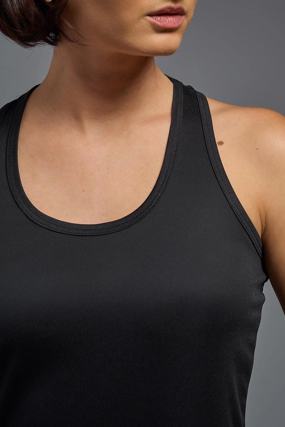 Black tank top worn by a person on a gray background