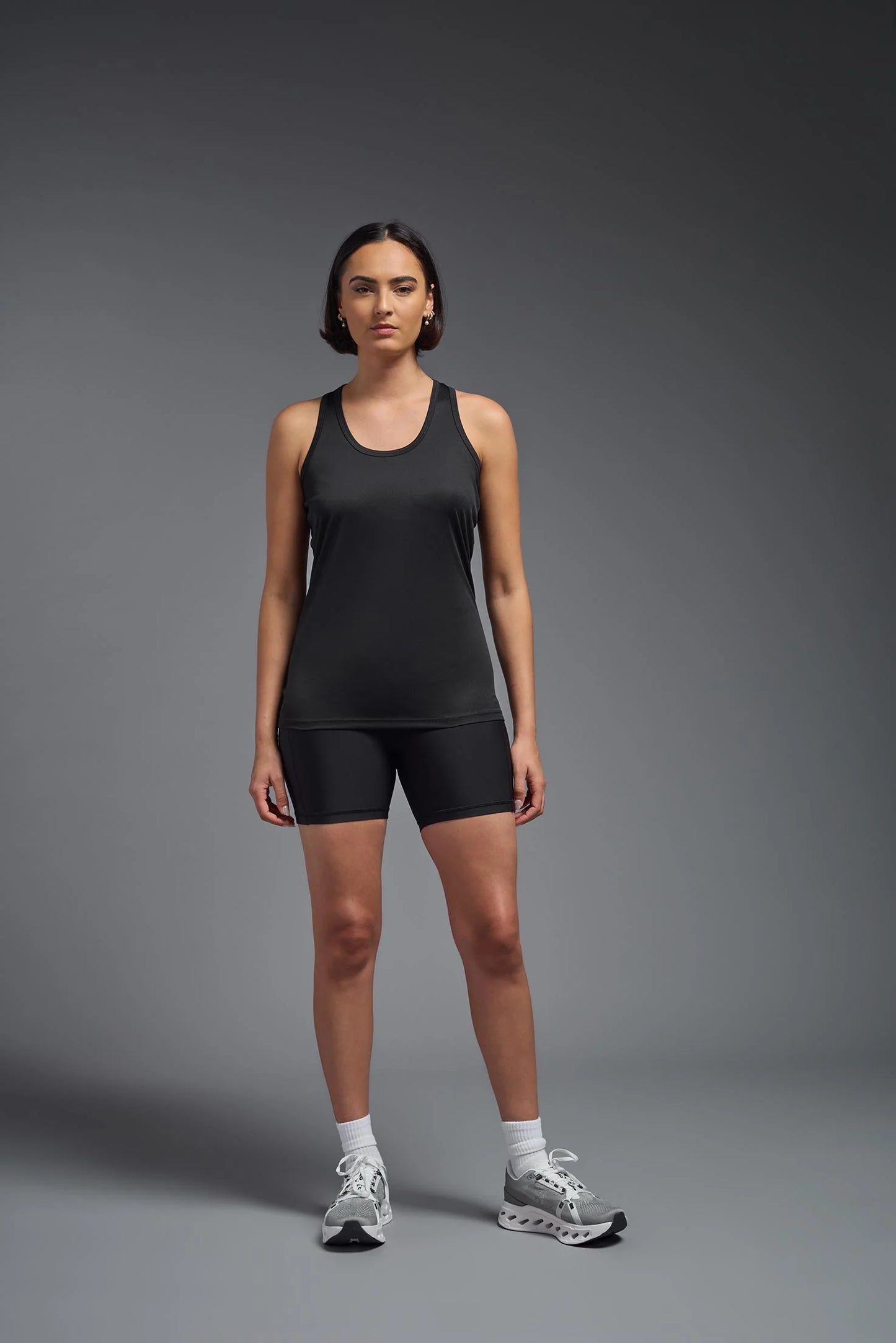 Woman wearing a black athletic outfit on a gray background