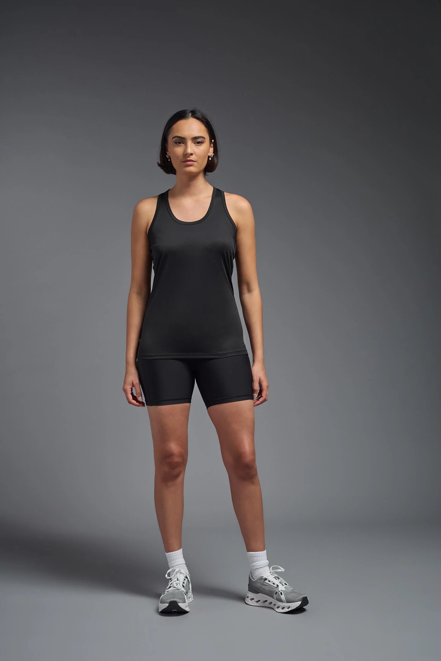 Woman wearing a black athletic outfit on a gray background